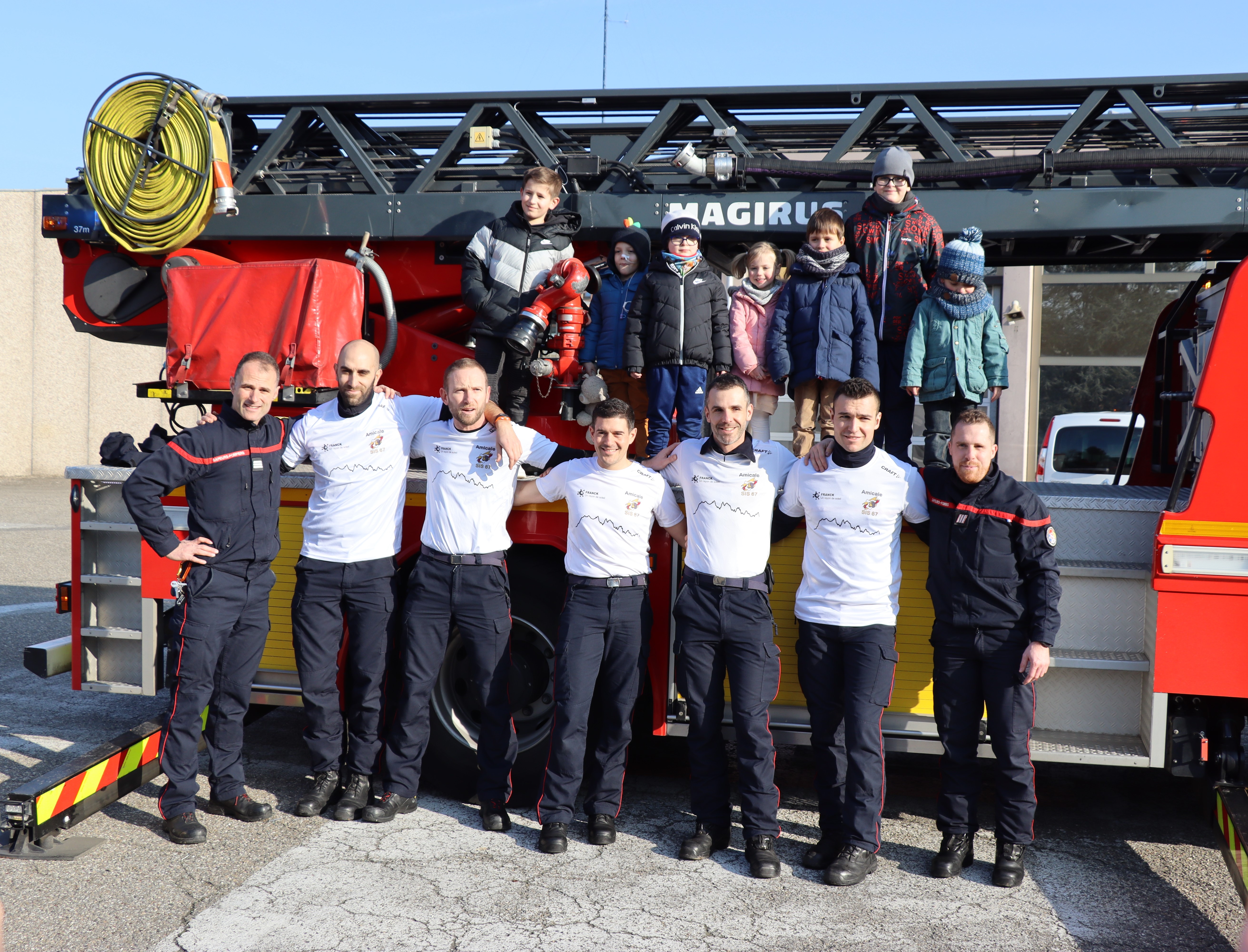 L'équipe de pompiers strasbourgeoise Les Diagonalsaciens posent devant un camion de pompier avec les enfants du CHRU de Strasbourg